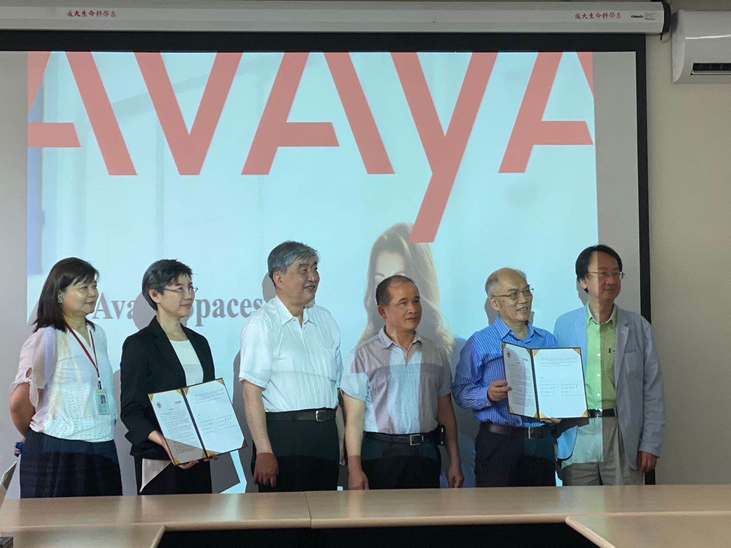 Six people stood together. Two of them are holding up certificates.