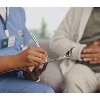 Nurse with clipboard talking to eldery patient
