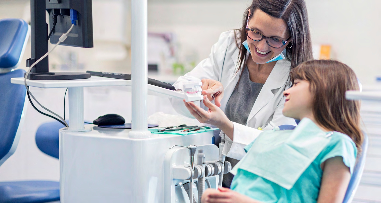 A dentist showing a child a teeth model