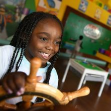 Girl holding a toy boat steering wheel