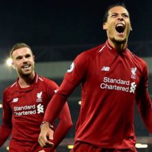 Liverpool football players in red jerseys with Standard Chartered sponsorship branding