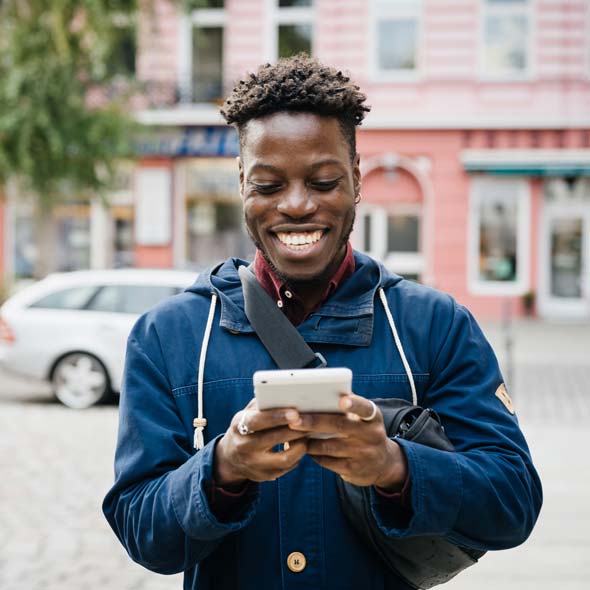 Man Smiling While Using Smartphone