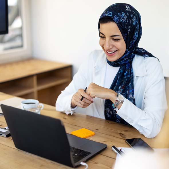 Happy middle eastern businesswoman with headscarf having video call with laptop