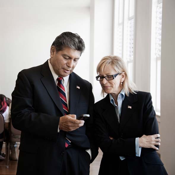 Two government employees looking at a cell phone 