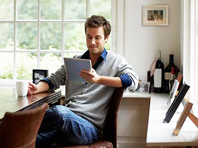 Man surfing net on digital tablet in his house