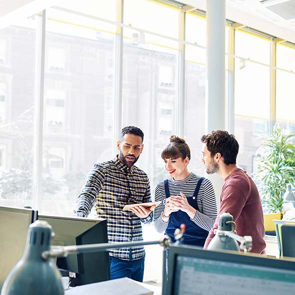 Creative coworkers stand to discuss a project