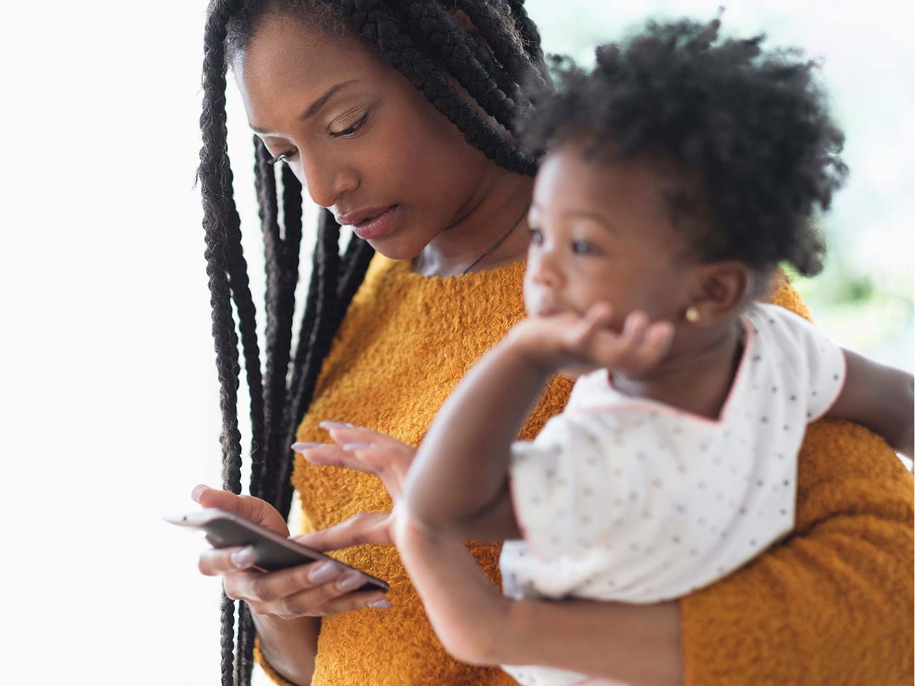 woman holding a baby reading a text message