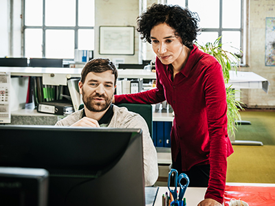 Office manager and employee looking at computer