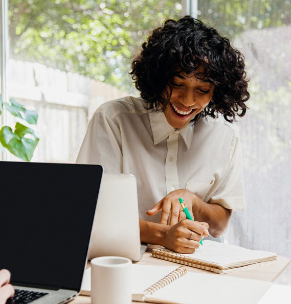 Woman smiling writing on a notepad.